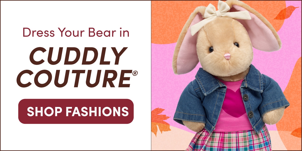 Dress Your Bear in CUDDLY COUTURE® graphic featuring Pawlette™, a light tan bunny plush with long floppy ears lined in pink and a cream bow on one ear. Pawlette wears a denim jacket over a pink heart-print top and a pink plaid skirt, posed against a pink and orange autumn-inspired background with scattered fall leaves. Text reads: Dress Your Bear in CUDDLY COUTURE® and SHOP FASHIONS.