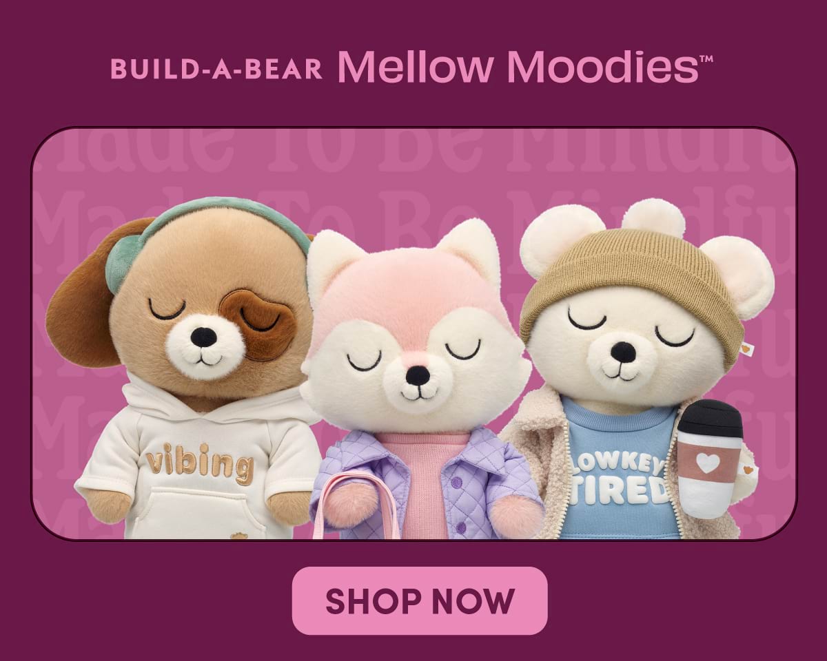 Build-A-Bear Mellow Moodies™ graphic featuring three plush characters with embroidered closed eyes against a pink and purple background. A puppy plush wears a cream hoodie with the text vibing, a pink fox plush wears a lavender quilted jacket, and a bear plush wears a tan beanie, sherpa jacket, and blue shirt that reads low key tired while holding a takeaway coffee cup with a heart icon. Text at the top reads BUILD-A-BEAR Mellow Moodies™ and a button at the bottom reads SHOP NOW.