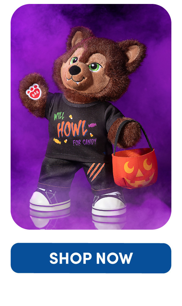 Purple foggy background sets a Halloween scene. In the forefront, werewolf plush holds a pumpkin basket and wearings jeans and a shirt that says Will Howl for Candy. Shop Now Button