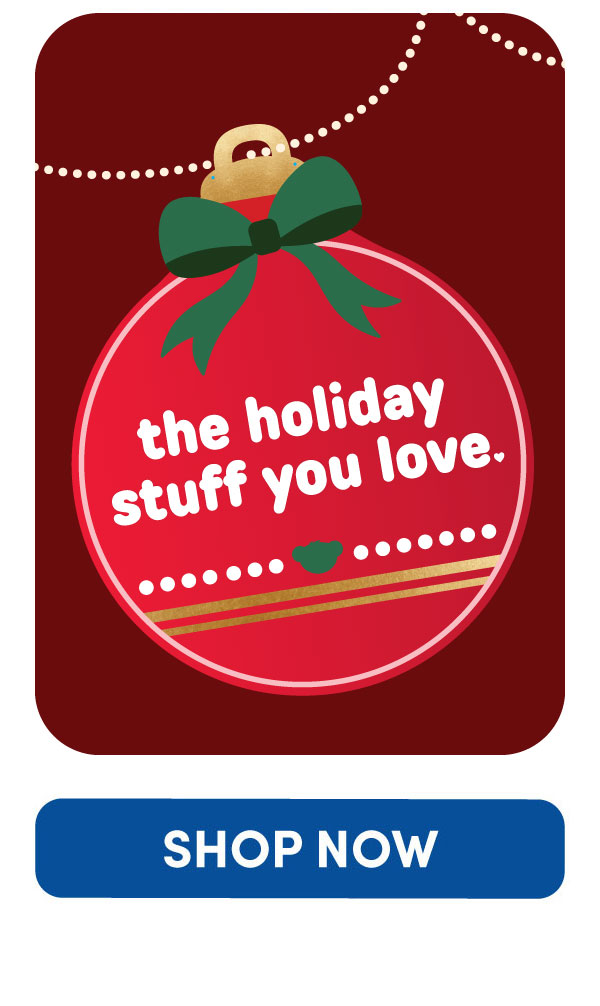 Holiday ornament graphic featuring a red ornament with a green bow hanging against a deep red background accented by a string of white holiday lights. The ornament displays playful Build-A-Bear-inspired messaging with a small green paw print detail near the bottom. Text reads: the holiday stuff you love.